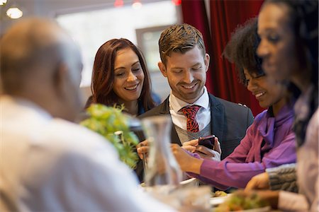 City life. A group of people on the go, keeping in contact, using mobile phones, and talking to each other. In a coffee shop. Stock Photo - Premium Royalty-Free, Code: 6118-07353718