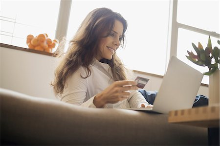 Woman on-line shopping on laptop on sofa with credit card Stock Photo - Premium Royalty-Free, Code: 6118-07353886