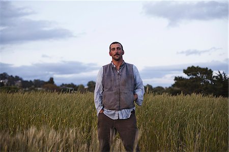 A man standing by a field of growing cereal crop, at the social care and work project, the Homeless Garden Project in Santa Cruz. Stock Photo - Premium Royalty-Free, Code: 6118-07353826