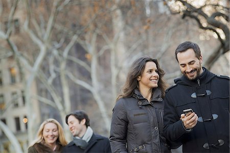 people group in the winter - Couple walking in urban park with smartphone Stock Photo - Premium Royalty-Free, Code: 6118-07353911