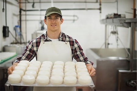 farmer - A small organic dairy farm with a mixed herd of cows and goats. Dairy building with large wheels of cheese maturing. Trays of produce. Stock Photo - Premium Royalty-Free, Code: 6118-07353917