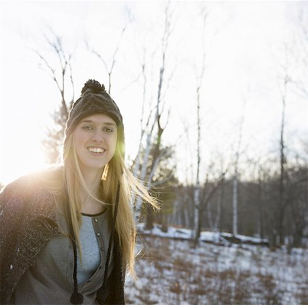 A young woman with blonde hair and a knitted woollen hat and coat. Outdoors on a winter's day. Snow on the ground. Photographie de stock - Premium Libres de Droits, Code: 6118-07354077