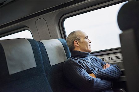 passager (homme et femme) - A mature man sitting in a window seat on a train journey, looking out into the distance. Photographie de stock - Premium Libres de Droits, Code: 6118-07354147