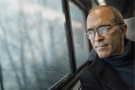 A mature man sitting in a window seat on a train journey, looking out into the distance. Photographie de stock - Premium Libres de Droits, Code: 6118-07354156