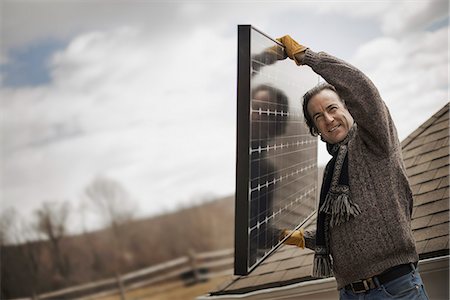 A man carrying a large solar panel across a farmyard. Photographie de stock - Premium Libres de Droits, Code: 6118-07354193