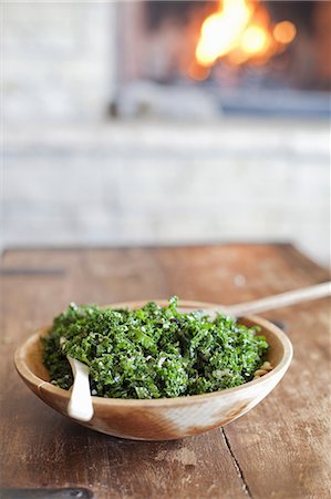 feu vert - A tabletop with a log fire in the background. Green leafy salad in a wooden bowl. Photographie de stock - Premium Libres de Droits, Code: 6118-07354121