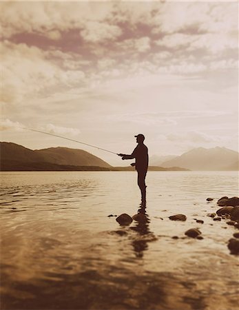Silhouette of a man flyfishing in calm waters on the Waschusett inlet in Glacier Bay national park in Alaska. Stock Photo - Premium Royalty-Free, Code: 6118-07354267