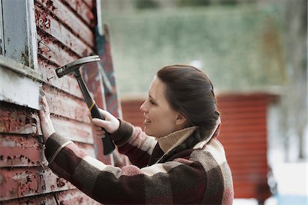 simsearch:6118-07353346,k - An organic farm in upstate New York, in winter. A woman with a hammer repairing the shingles on a barn. Stock Photo - Premium Royalty-Free, Code: 6118-07354287