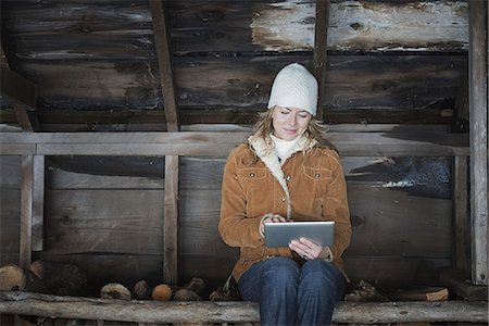 An organic farm in upstate New York, in winter. A woman sitting in an outbuilding using a digital tablet. Stock Photo - Premium Royalty-Free, Code: 6118-07354290