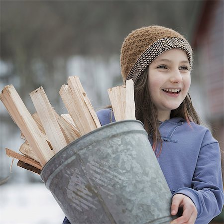 farm chores - An organic farm in winter in New York State, USA. A girl carrying a bucket full of kindling and firewood. Stock Photo - Premium Royalty-Free, Code: 6118-07354219