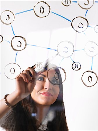 A young woman writing a chemical notation for the gas Oxygen, the molecular structure, on a clear seethrough panel with a black pen. Photographie de stock - Premium Libres de Droits, Code: 6118-07354228