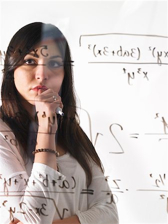 simsearch:6111-06727550,k - A young woman looking at a mathematical equation written out with black marker on a clear seethrough wall. Photographie de stock - Premium Libres de Droits, Code: 6118-07354231