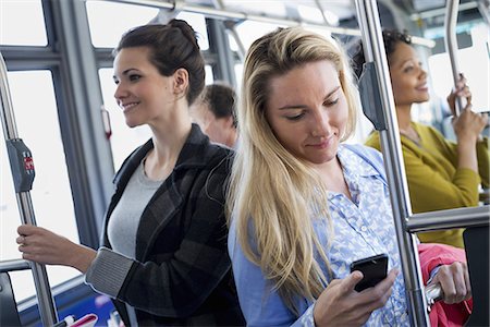 New York City park. People, men and women on a city bus. Public transport. Keeping in touch. A young woman checking or using her cell phone. Stock Photo - Premium Royalty-Free, Code: 6118-07354342