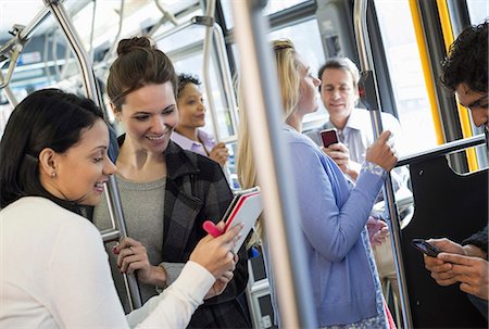 sophisticated - New York City park. People, men and women on a city bus. Public transport. Two women looking at a handheld digital tablet. Stock Photo - Premium Royalty-Free, Code: 6118-07354344