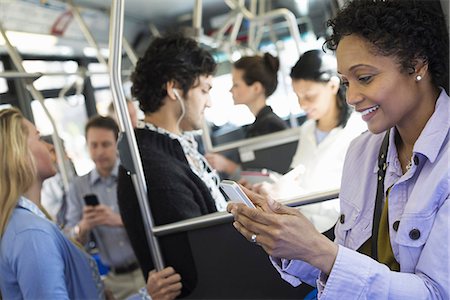six people - New York City park. People, men and women on a city bus. Public transport. Keeping in touch. A young woman checking or using her cell phone. Stock Photo - Premium Royalty-Free, Code: 6118-07354345