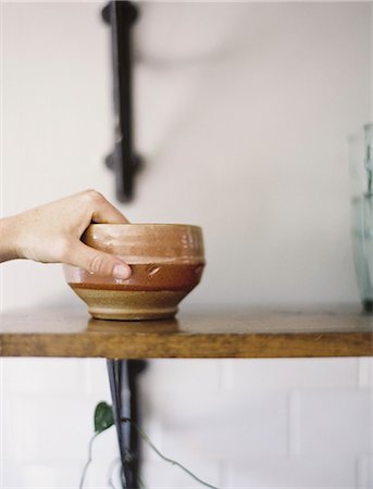 simsearch:6118-07354411,k - Farm to Table. A person reaching up for a pottery bowl in a domestic kitchen. Stock Photo - Premium Royalty-Free, Code: 6118-07354383