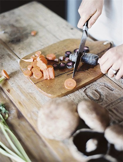 A domestic kitchen tabletop. A person chopping fresh vegetables on a chopping board with a knife. Foto de stock - Sin royalties Premium, Código de la imagen: 6118-07354392