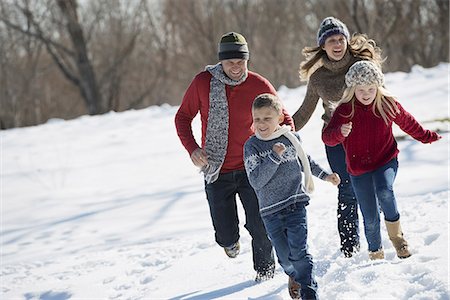 simsearch:6118-07354307,k - Winter scenery with snow on the ground. Family walk. Two adults chasing two children. Stockbilder - Premium RF Lizenzfrei, Bildnummer: 6118-07354459