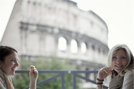 Two women seated on a terrace overlooking the huge Roman amphitheatre building, the Colosseum in Rome. Photographie de stock - Premium Libres de Droits, Code: 6118-07354479