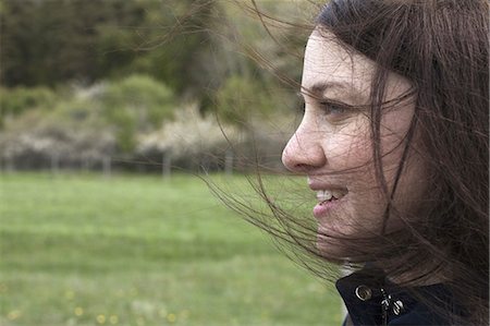 simsearch:6118-07354480,k - A young woman in profile. Her brown hair blowing about her face. Outdoors. Spring. Stock Photo - Premium Royalty-Free, Code: 6118-07354483