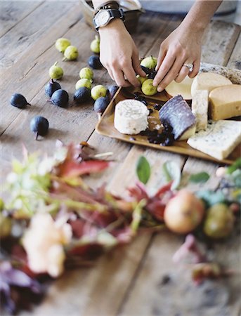 préparations - A woman at a domestic kitchen table. Arranging fresh fruit, black and green figs on a cheese board. Organic food. From farm to plate. Photographie de stock - Premium Libres de Droits, Code: 6118-07354403