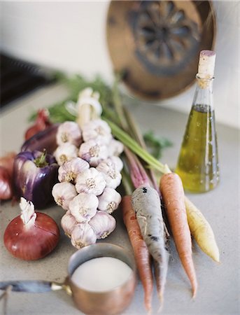 A tabletop. A group of fresh organic vegetables, carrots and onions, garlic and peppers. A flask of oil, and a copper pan of sauce. Photographie de stock - Premium Libres de Droits, Code: 6118-07354401