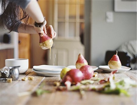 A woman in a domestic kitchen cooking. Dipping fresh organic pears into a sauce for dessert. Fresh ingredients. Brown sugar cubes Foto de stock - Sin royalties Premium, Código: 6118-07354411