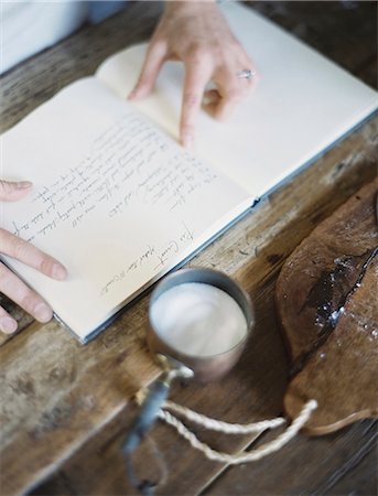 simsearch:6118-07354388,k - A woman in a domestic kitchen, reading a recipe book. Stock Photo - Premium Royalty-Free, Code: 6118-07354422