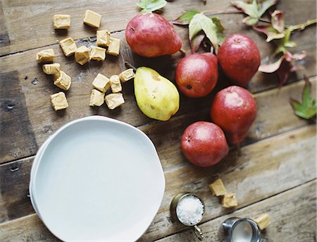 A domestic kitchen tabletop. A small group of fresh organic pears and a stack of white plates. Stock Photo - Premium Royalty-Free, Code: 6118-07354432