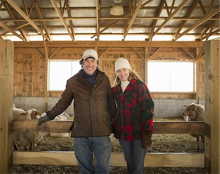 An Organic Farm in Winter in Cold Spring, New York State. A farmer and a woman standing by a pen full of sheep. Stock Photo - Premium Royalty-Free, Code: 6118-07354438