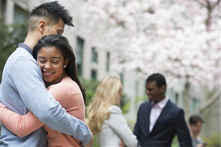 City life in spring. Young people outdoors in a city park. A couple embracing, and two people talking under the trees. Foto de stock - Sin royalties Premium, Código: 6118-07354545