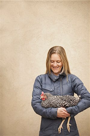 A woman wearing a grey coat and holding a chicken. Stock Photo - Premium Royalty-Free, Code: 6118-07354594