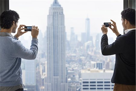 simsearch:6118-07354511,k - Urban lifestyle. Two young men using their phones to take images of the city from an observation platform overlooking the Empire State Building. Foto de stock - Sin royalties Premium, Código: 6118-07354523