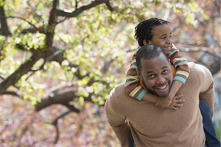 funny man looking at camera - A New York city park in the spring. Sunshine and cherry blossom. A father carrying his son on his shoulders. Stock Photo - Premium Royalty-Free, Code: 6118-07354679