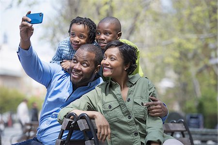 family outside ethnic - A New York city park in the spring. A family, parents and two boys taking a photograph with a smart phone. Stock Photo - Premium Royalty-Free, Code: 6118-07354685