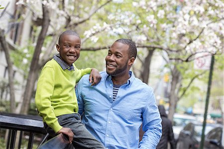family lifestyle funny - A New York city park in the spring. Sunshine and cherry blossom. A boy sitting on a fence, beside his father. Stock Photo - Premium Royalty-Free, Code: 6118-07354695