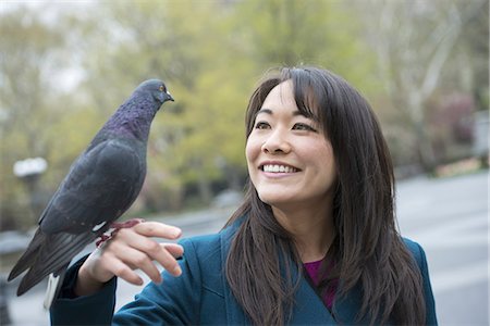 A young woman in the park with a pigeon perched on her wrist. Foto de stock - Sin royalties Premium, Código: 6118-07354631