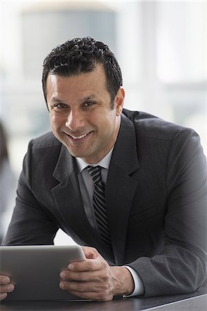 Young professionals at work. A man in a business suit, using a digital tablet. Stock Photo - Premium Royalty-Free, Code: 6118-07354763