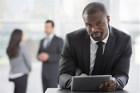 simsearch:6118-07351370,k - Young professionals at work. A man in a business suit, using a digital tablet. Foto de stock - Sin royalties Premium, Código: 6118-07354761