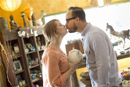 Two people, a couple running an antique store. Small business. Kissing each other. Stock Photo - Premium Royalty-Free, Code: 6118-07440351