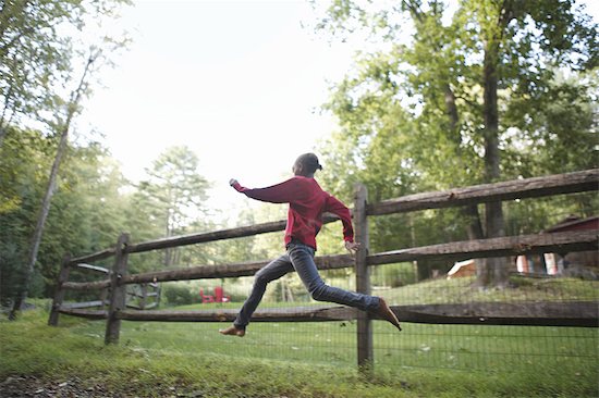 A boy running around a paddock fence outdoors. Photographie de stock - Premium Libres de Droits, Le code de l’image : 6118-07440358