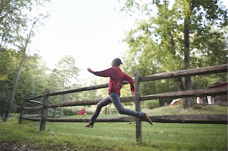 frische luft - A boy running around a paddock fence outdoors. Stockbilder - Premium RF Lizenzfrei, Bildnummer: 6118-07440358