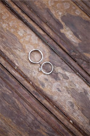 Platinum wedding rings . Two rings on a worn scrubbed stained wooden surface. Stock Photo - Premium Royalty-Free, Code: 6118-07440677