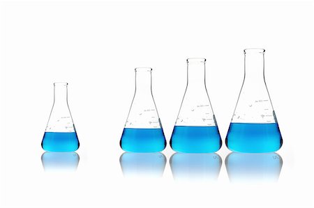 Conical glass scientific flasks holding blue liquids. Lined up in size order, with one set apart. Foto de stock - Sin royalties Premium, Código: 6118-07440734