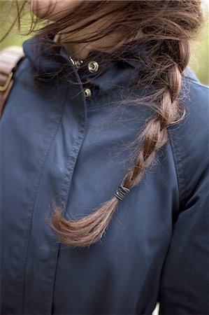 simsearch:6118-07354480,k - A woman with long brown hair plaited in a braid. Wearing a blue leather jacket. Close up. Stock Photo - Premium Royalty-Free, Code: 6118-07440870