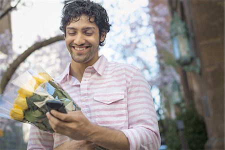 park decoration - City life. A young man in the park in spring, using a mobile phone.  Holding a bunch of yellow roses. Stock Photo - Premium Royalty-Free, Code: 6118-07440875