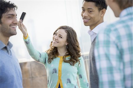 simsearch:878-07442442,k - New York City. An observation deck overlooking the Empire State Building. A woman using a smart phone to take an image. Three young men. Foto de stock - Sin royalties Premium, Código: 6118-07440876