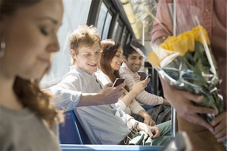 Urban Lifestyle. A group of people, men and women on a city bus, in New York city. Two people checking their smart phones. Stock Photo - Premium Royalty-Free, Code: 6118-07440881