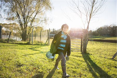 A young boy in an animal paddock, holding a bucket of feed. Animal sanctuary. Stockbilder - Premium RF Lizenzfrei, Bildnummer: 6118-07439820