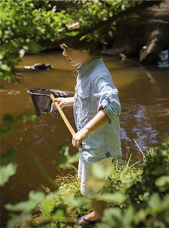 A young boy holding a fishing net, by a shallow river. Camping in the New Forest. Stock Photo - Premium Royalty-Free, Code: 6118-07521778